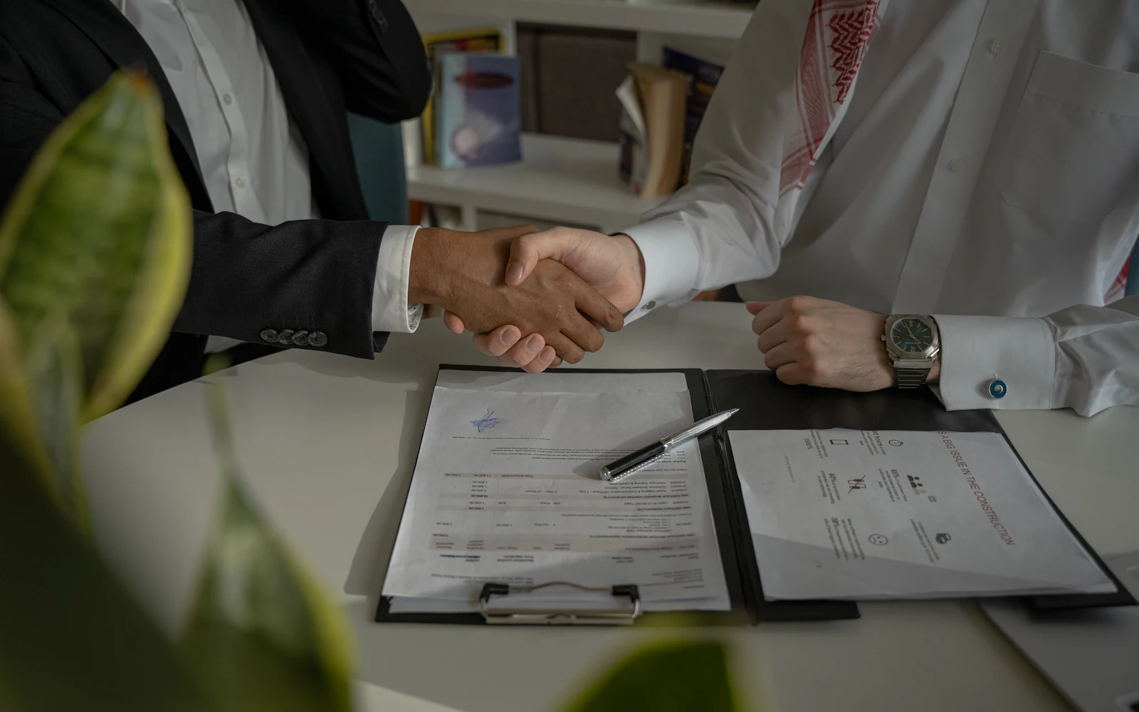 Two people shaking hands over documents on a table